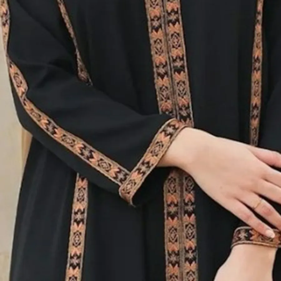 Close-up of a navy abaya with woven gold trim